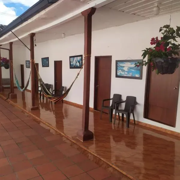 Corredor colonial con hamacas y acceso a habitaciones